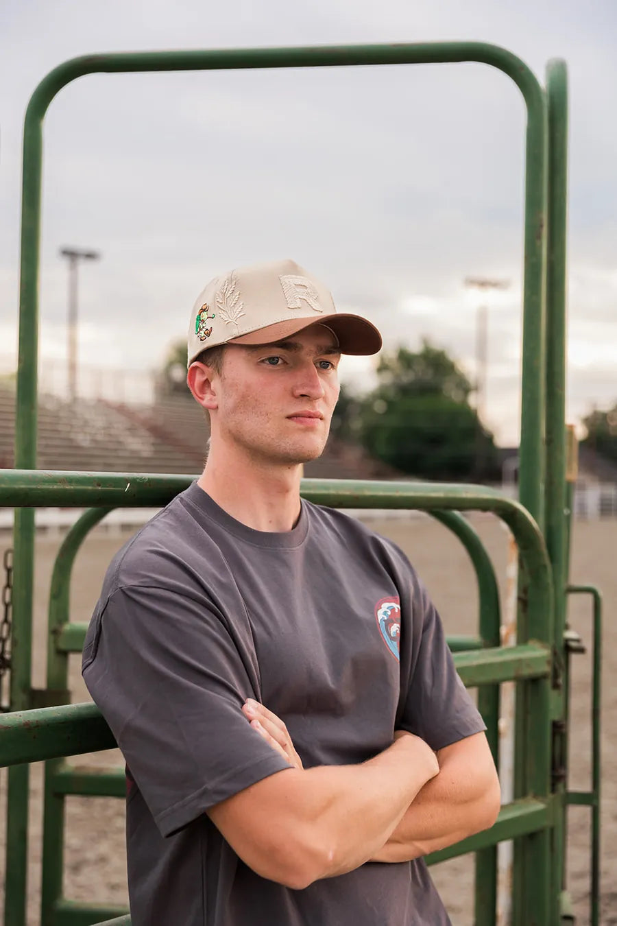 Tan Croma hat, arms crossed at the rodeo chute gate