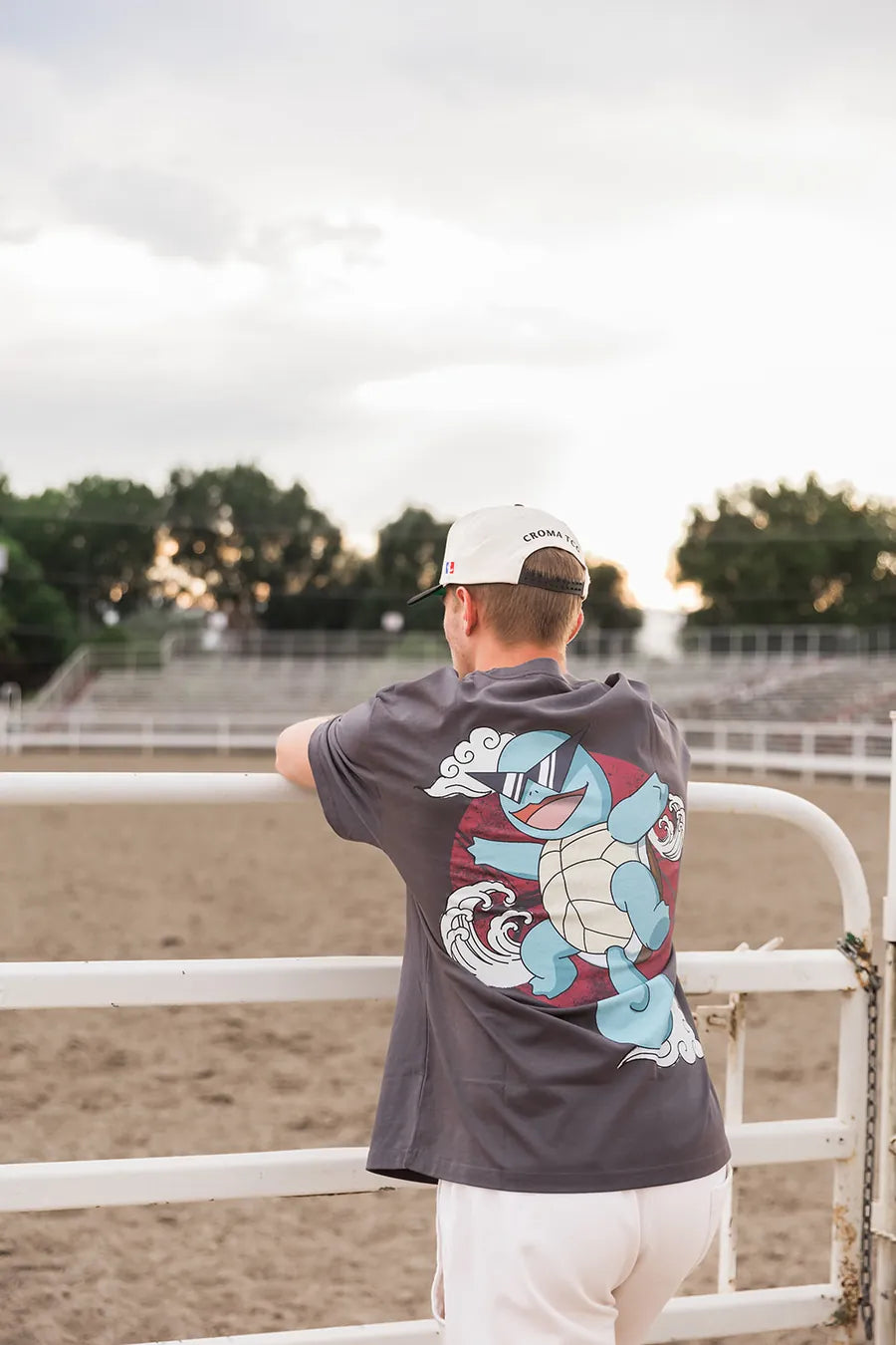 Squirtle Squad back print, leaning on the arena rail at sunset